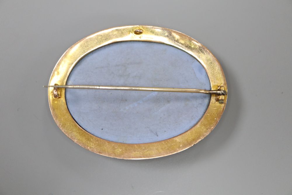 A late Victorian yellow metal mounted oval Wedgwood plaque brooch, depicting a maiden with chariot and horses,